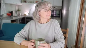 Woman quietly reflecting at a kitchen table while considering alternatives to AA