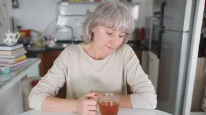 Woman sitting quietly at a kitchen table feeling emotionally drained the morning after drinking