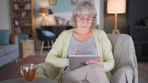 Woman relaxing at home in the evening playing solitaire on an iPad while adjusting to life without alcohol.