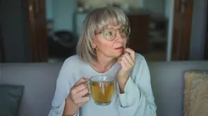 Woman sitting quietly at home in the evening, reflecting while hesitating during a familiar nightly drinking routine