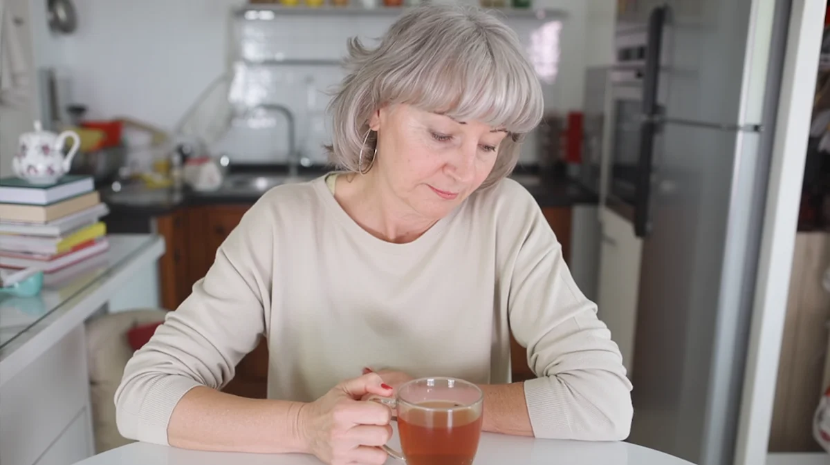Woman sitting quietly at a kitchen table feeling emotionally drained the morning after drinking