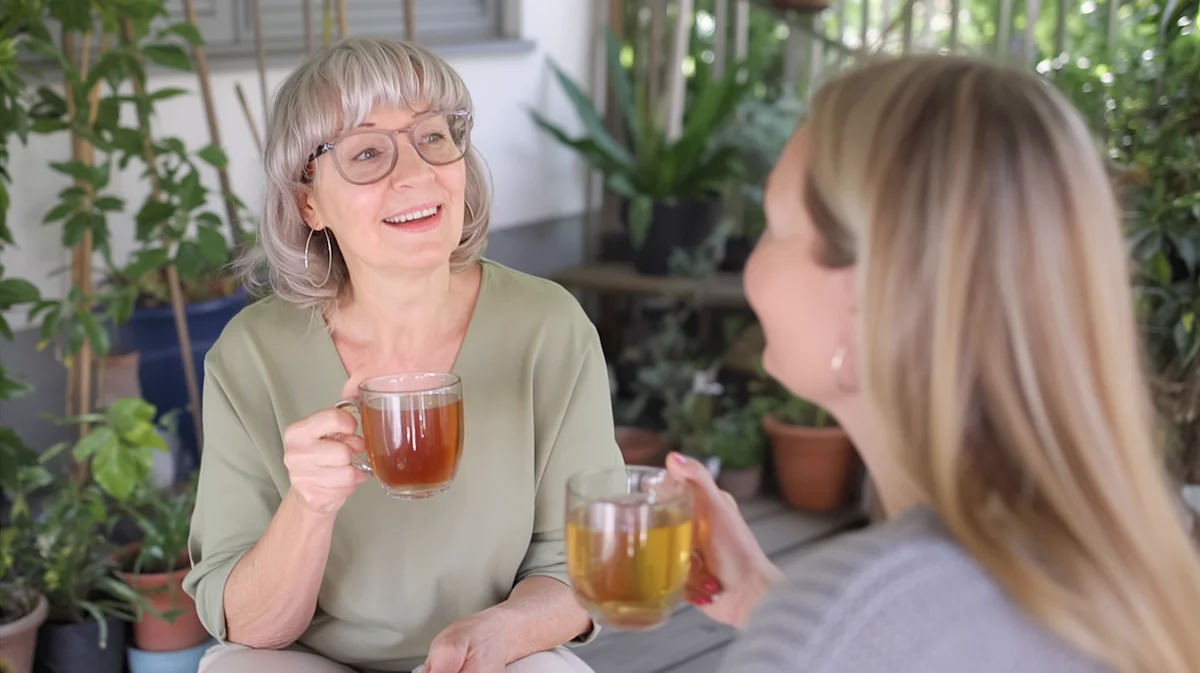 Woman enjoying tea and a relaxed outdoor conversation with a neighbor while embracing life without alcohol.