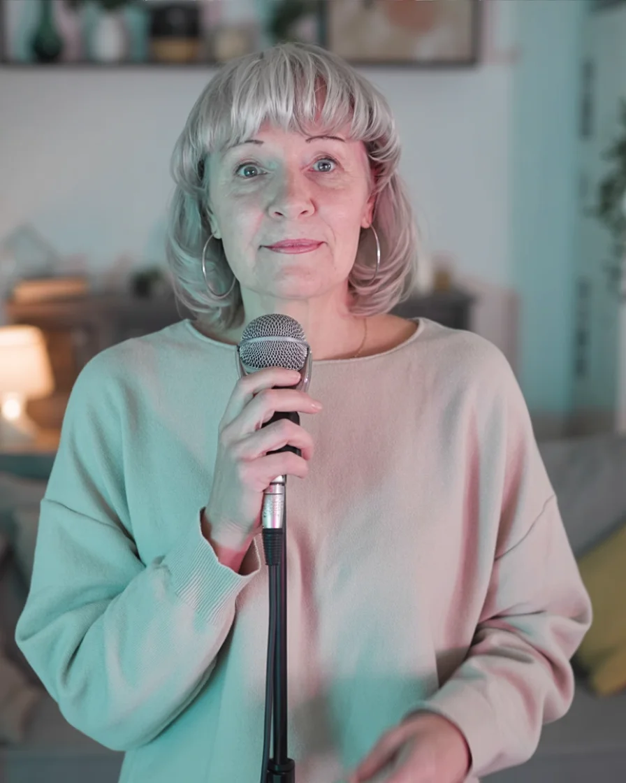 Susan singing the Live Better Sober theme song into a microphone in a softly lit room