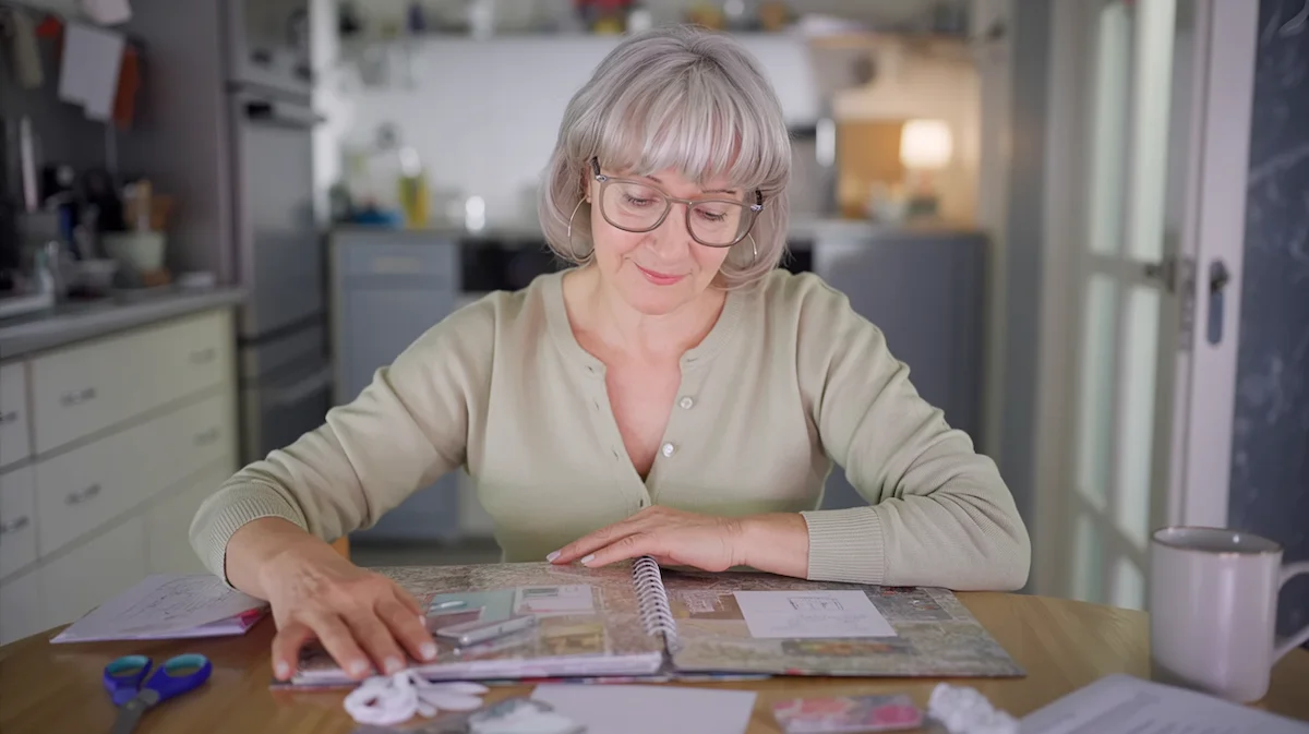 What happens when you stop drinking every night calm evening routine Woman sitting at table creating scrapbook in a calm evening routine without alcohol