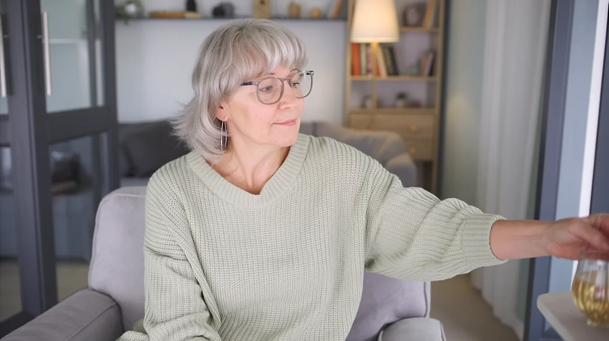 Woman pausing and reaching in evening at home, reflecting a repeated drinking pattern at the same time