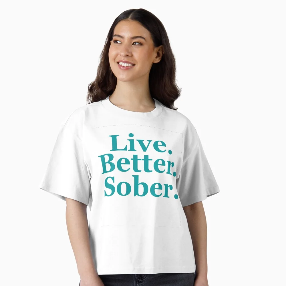Woman wearing a white “Live. Better. Sober.” typography oversized T-shirt.