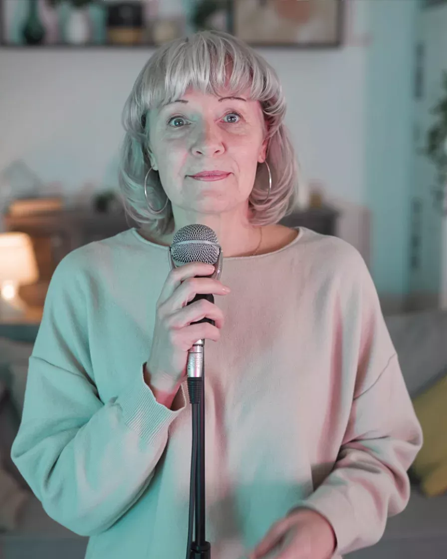 Susan singing the Live Better Sober theme song into a microphone in a softly lit room